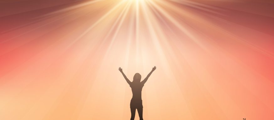 Silhouette of a female with her arms raised against a sunset sky